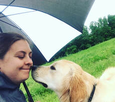 Dog kisses trainer under an umbrella